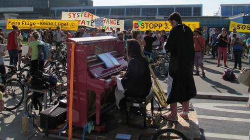Open Piano for Refugees bei der Kundgebung, im Hintergrund einige der Transparente